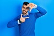 © Krakenimages.com - Young hispanic man with beard wearing casual blue sweater smiling making frame with hands and fingers with happy face. creativity and photography concept.