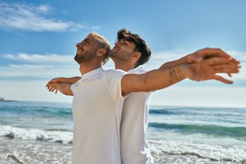 Young gay couple smiling happy breathing at the beach.