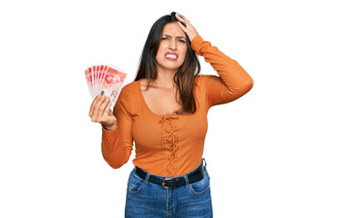 Wall Mural - Beautiful hispanic woman holding 20 israel shekels banknotes stressed and frustrated with hand on head, surprised and angry face