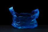 Fototapeta  - Plastic blue bag on a black background. Transparent blue package on a dark background.