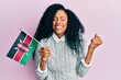 Middle age african american woman holding kenya flag screaming proud, celebrating victory and success very excited with raised arm