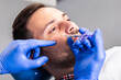 © hedgehog94 - Handsome young man is getting a rejuvenating facial injections. He is sitting calmly at clinic. The expert beautician is filling male wrinkles by hyaluronic acid.