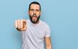 © Krakenimages.com - Young man with beard wearing casual white t shirt pointing displeased and frustrated to the camera, angry and furious with you