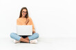 © luismolinero - Young woman with a laptop sitting on the floor celebrating a victory
