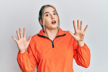 Wall Mural - Young modern girl wearing sports sweatshirt afraid and terrified with fear expression stop gesture with hands, shouting in shock. panic concept.