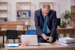 © Elnur - Old male employee auditor holding loupe at workplace