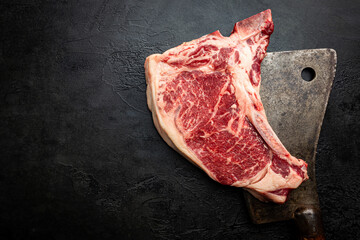 Wall Mural - Raw fresh meat T-bone beef Steak and butcher knife on black background, top view