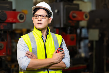 Factory engineering manager asian man Working and holding radio walkie talkie at Metal lathe industrial manufacturing factory. Portrait of  Engineer Operating lathe Machinery.