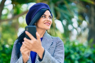 Wall Mural - Young beautiful woman wearing french style using smartphone at the park.