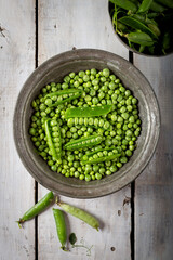 Wall Mural - Fresh green peas. Top view. Fresh green peas pods and green peas in bowl on wooden background.