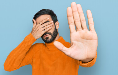 Wall Mural - Young hispanic man wearing casual clothes covering eyes with hands and doing stop gesture with sad and fear expression. embarrassed and negative concept.