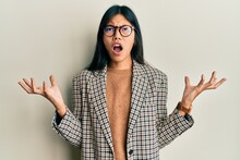 Young Chinese Woman Wearing Business Style And Glasses Crazy And Mad Shouting And Yelling With Aggressive Expression And Arms Raised. Frustration Concept.