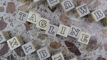 Fototapete - Tagline concept with the word on wood blocks and upper and lower borders of wooden cubes with random letters over a marbled stone background. Rotating table