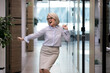 © fizkes - Happy mature Caucasian woman worker dance have fun in office, enjoy Friday time at workplace. Overjoyed middle-aged businesswoman or employee celebrate work achievement or job success.