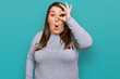 Beautiful brunette plus size woman wearing casual clothes doing ok gesture shocked with surprised face, eye looking through fingers. unbelieving expression.