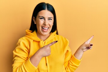 Sticker - Beautiful brunette woman wearing casual sweatshirt smiling and looking at the camera pointing with two hands and fingers to the side.