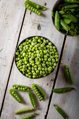 Wall Mural - Fresh green peas. Top view. Fresh green peas pods and green peas in bowl on wooden background.