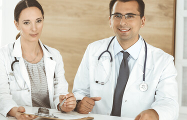 Two doctors discussing treatment problems while sitting at the desk in hospital office. Data in medicine and health care concept