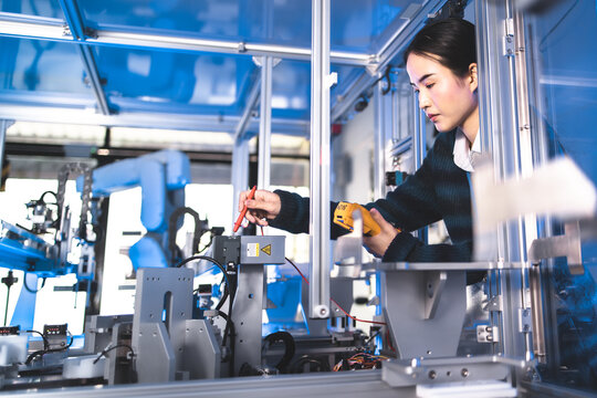 Female Engineers Maintenance Robot Arm at Lab. She are in a High Tech Research Laboratory with Modern Equipment. Technology and Innovation Concept.Professional Japanese Development Engineer is Testing
