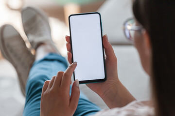Woman hold mobile phone in hands, lying on sofa
