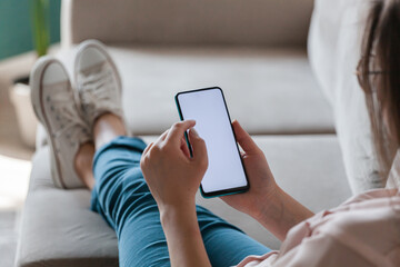 Woman hold mobile phone in hands, lying on sofa