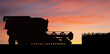 Silhouette of combine harvester at sunset
