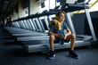 Youngster with water sitting on treadmill in gym