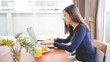 © mojo_cp - Asian businesswoman having lunch break and  typing on the laptop. working at home concept.