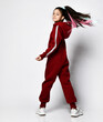 Caucasian pretty preteen girl model with trendy hairstyle dressed sportswear tracksuit turning to camera from her back. Full-length studio portrait on copy space. Advertisement concept. Kids fashion