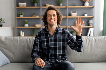 Poster - Cheerful Guy Waving Hand Sitting On Sofa At Home