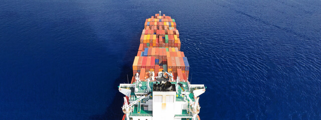 Aerial drone ultra wide photo of huge container ship cruising deep blue open ocean sea near logistics container terminal port