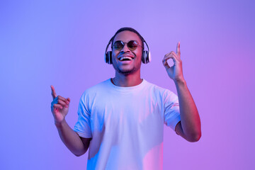 Wall Mural - Cheerful Black Guy In Stylish Eyeglasses Enjoying Listening Music In Wireless Headphones