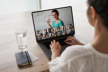 remote online working woman sitting on a work desk with laptop in in her home office joining an online meeting or watching video conference or webinar presentation