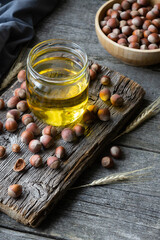 Wall Mural - Hazelnut oil, filbert and cooking oil in glass of jar on wooden backdrop, heap or stack of hazelnuts, healty food