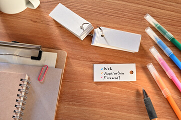 Poster - there is a a word card with web application firewall written on it. they are on the desk along with 