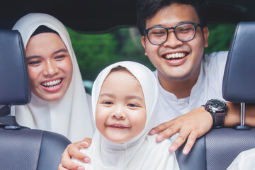 Wall Mural - Muslim parents laughing with daughter inside car