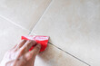 Floor tile fixing and renovation, Hand using trowel repairing old tile grout in bathroom
