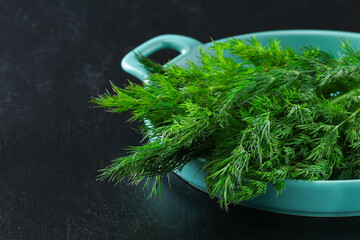 Green culinary herb dill on a black background. dill in a blue dish.