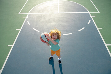 Poster - Cute smiling boy plays basketball. Kid shooting basketball ball and playing basketball. Healthy children lifestyle, outdoor on playground.