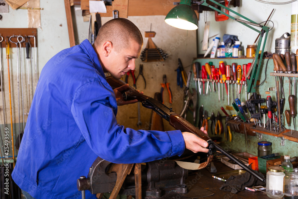 Fotografie Gunsmith examines an automatic rifle before being repaired ...