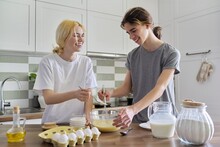 Teenagers guy and girl cooking pancakes in kitchen together