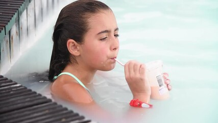 Canvas Print - Young girl relaxing sipping fruit juice in a natural pool Slow motion