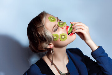 Fashion photo of woman posing with slices of kiwi on her face