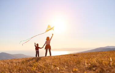 Wall Mural - Happy family  mother and son  launch  kite on nature at sunset
