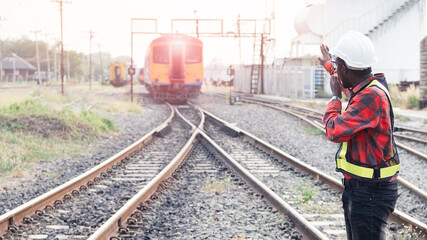 African engineer   raised a hand to control a the train on railway with talking by radio communication or walkie talkie