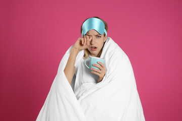 Sticker - Young woman in sleeping mask wrapped with blanket holding cup on pink background