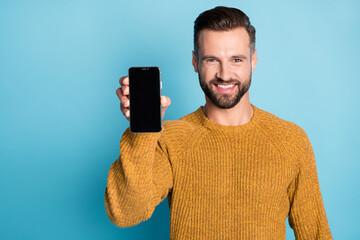 Wall Mural - Photo of young happy cheerful smiling positive handsome man demonstrate phone isolated on blue color background