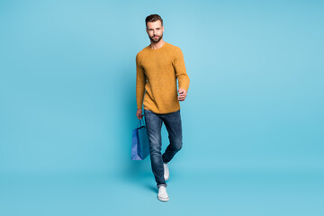 Canvas Print - Full sie photo of young confident serious handsome man go walk hold shopping bag isolated on blue color background