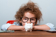 Sad Child Girl Put Coins In Piggy Bank. Business School And Financial Education For Children. Kid In Glasses With Little White Piggy Bank. Think Idea Innovation Investment