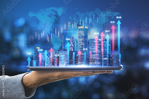 Obraz Dibond Business development concept with digital tablet on human palm with glowing night megapolis city skyline and vertical blue and pink growing arrows on world map with financial graphs background